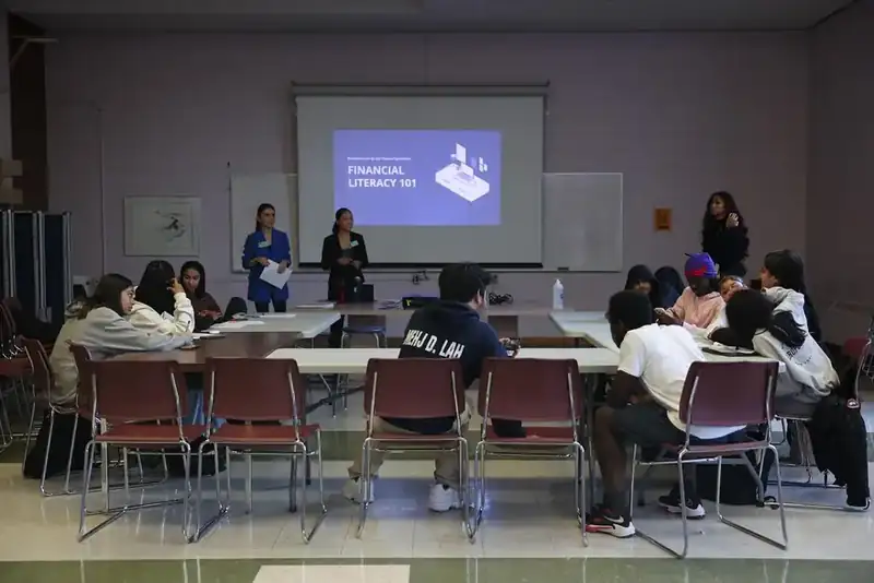 Youth seated in a classroom watching a Financial Literacy 101 presentation